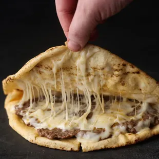 a hand holding a piece of cheese pizza