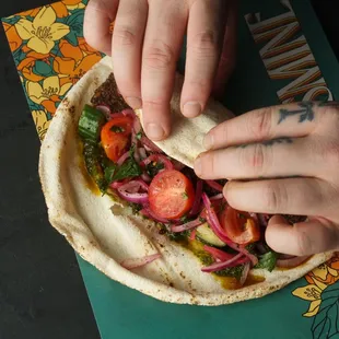 a person putting a piece of food on a tortilla