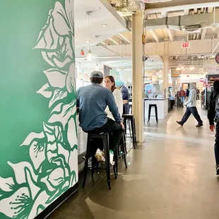a man sitting on a stool in front of a green wall