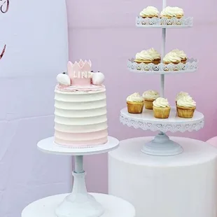 a three tiered cake and cupcakes