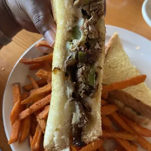 Close up on the Philly cheesesteak sandwich with sweet potato fries