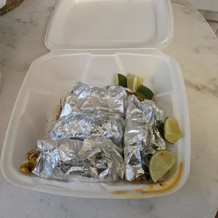 4 tacos wrapped up and lime wedges