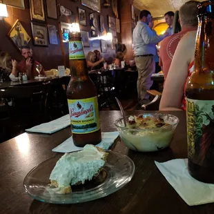 a woman sitting at a table with a plate of food and a bottle of beer