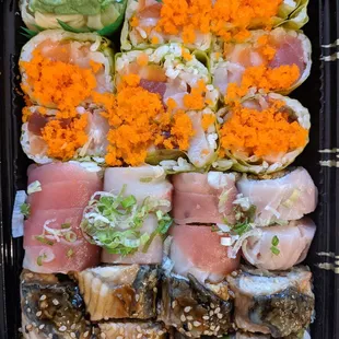 a tray of sushi and vegetables