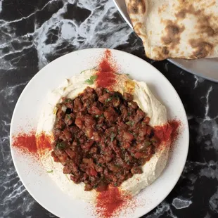 One of most popular appetizers hummus topped with lamb served with fresh tandoori bread