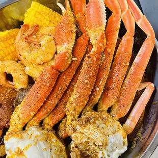 a plate of crab legs, shrimp, corn, potatoes, and corn on the cob