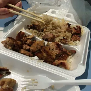 a tray of food with rice, meat and chopsticks