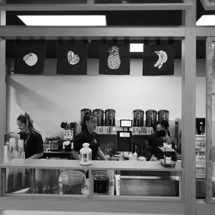 a black and white photo of a woman behind a counter