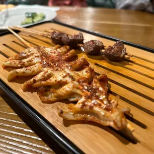 skewers of meat on a wooden tray