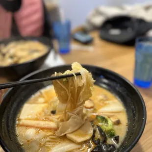 a bowl of soup with chopsticks