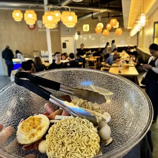 a person holding a bowl of noodles