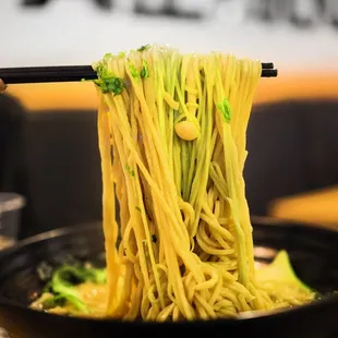 a bowl of noodles with chopsticks