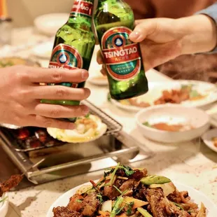 two people holding beer bottles