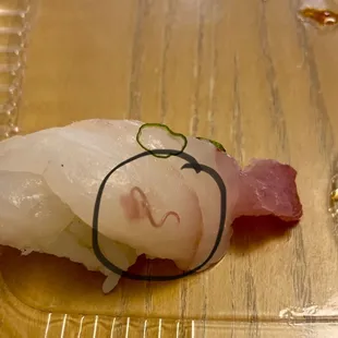 Piece of white fish sushi with a worm