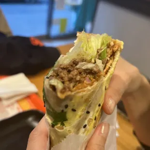 a person holding a burrito in their hand
