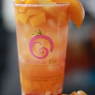 a glass of iced tea with sliced peaches