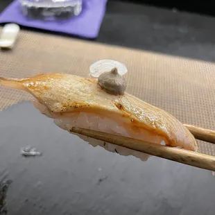 a piece of sushi being held by chopsticks