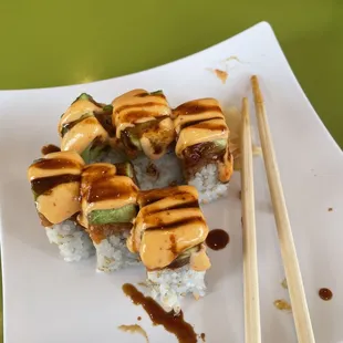 a plate of sushi with chopsticks