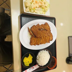 a plate of fried chicken, rice, and a bowl of coleslaw