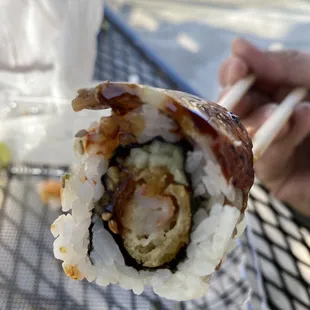 a hand holding a piece of sushi