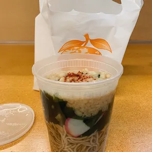 a plastic cup filled with noodles and vegetables