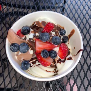 a bowl of yogurt with strawberries and blueberries