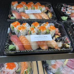 a variety of sushi in plastic containers