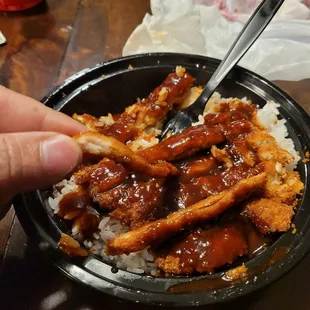 a hand holding a fork over a bowl of food