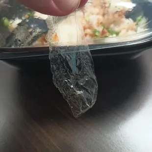 a hand holding a piece of food wrapped in plastic
