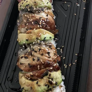 a sushi roll with avocado and sesame seeds