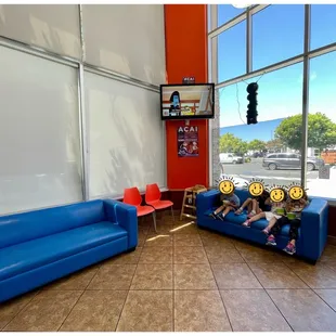 a waiting area with blue couches and red chairs