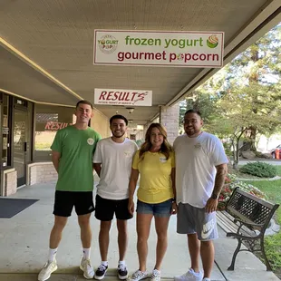 a group of people standing in front of a frozen yogurt shop