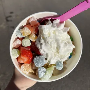 With rainbow mochi, strawberries, peanuts, and whipped cream in the cutest container you can&apos;t see the design of.