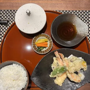 Shrimp tempura, rice, tsukemono, tempura dipping sauce, udon appetizer under the white dome.