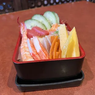 a tray of sushi and vegetables on a table