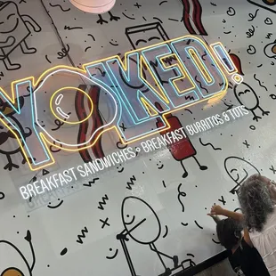 a man sitting in front of a neon sign