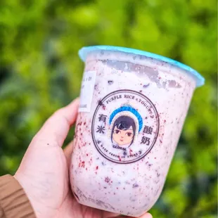 a hand holding a cup of yogurt