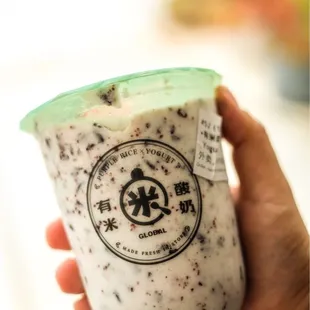 a hand holding a cup of yogurt