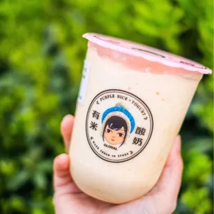 a hand holding a cup of yogurt