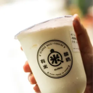 a hand holding a cup of yogurt