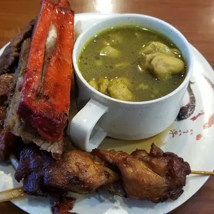 a bowl of soup and skewers