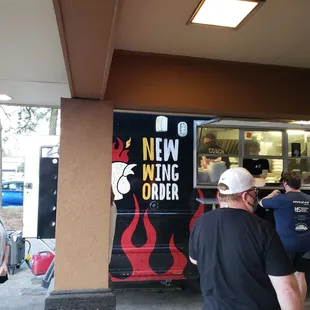 a line of people waiting outside a new wing order truck