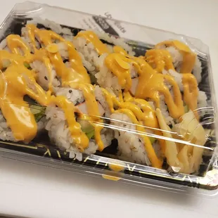a container of sushi with cheese sauce