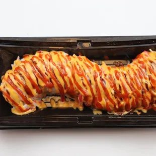 a black plate with a roll covered in cheese and sauce