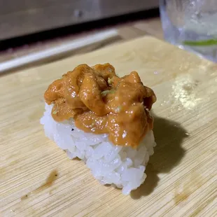 a piece of sushi on a wooden cutting board