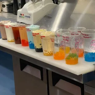 a row of boba cups on a counter