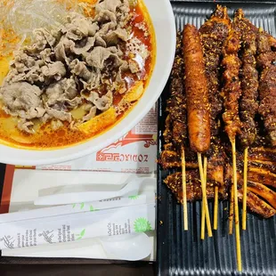 a bowl of soup and a plate of meat skewers