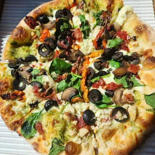 Chicken pesto 10in pie with sun dried tomatoes, black olives, basil, artichoke, bacon, and mushrooms