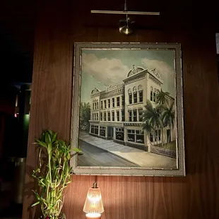 a painting of a building and a lamp on a table