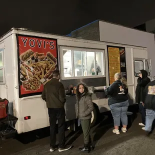 a group of people standing in front of a food truck
